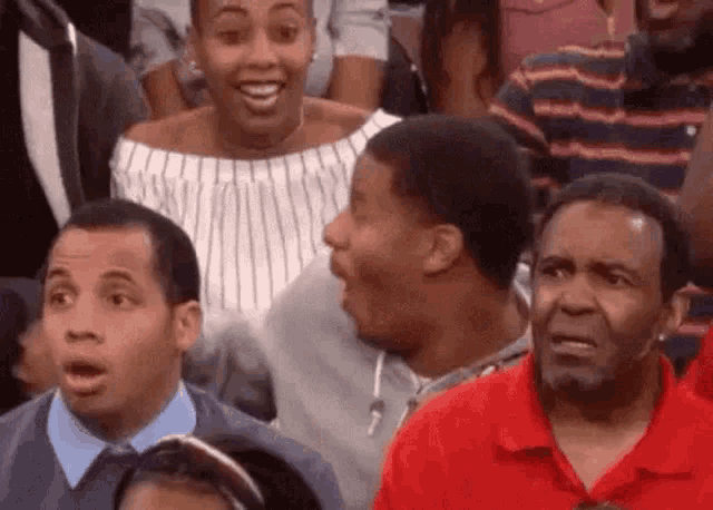 a group of people are sitting in a stadium with their mouths open and their faces surprised .