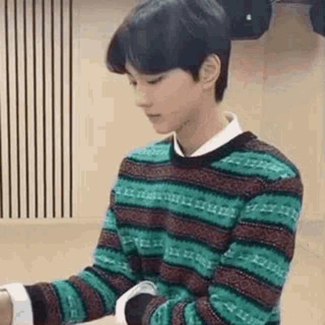 a young man is wearing a striped sweater and a watch .