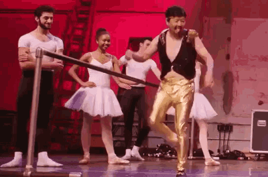 a man in gold pants is dancing on a stage with a group of ballerinas .