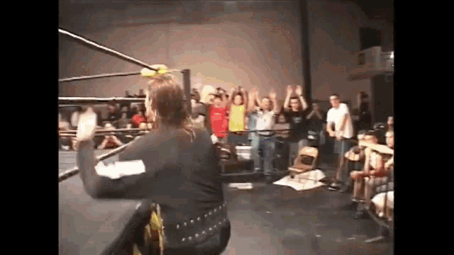 a group of people are standing in a wrestling ring watching a match .