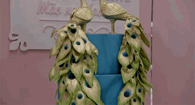 a blue cake decorated with peacock feathers and two peacocks