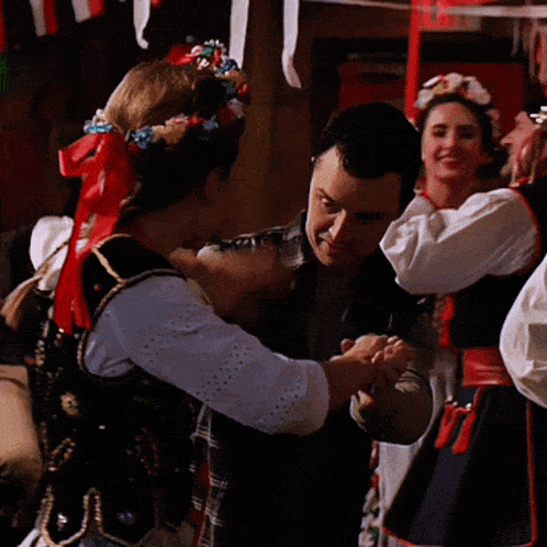 a woman wearing a black vest and a red necklace is dancing with a man