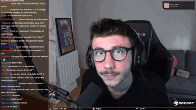 a man wearing glasses and headphones sitting in front of a microphone with a roccat logo in the corner