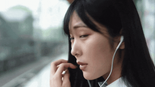 a woman wearing ear buds looks down at something