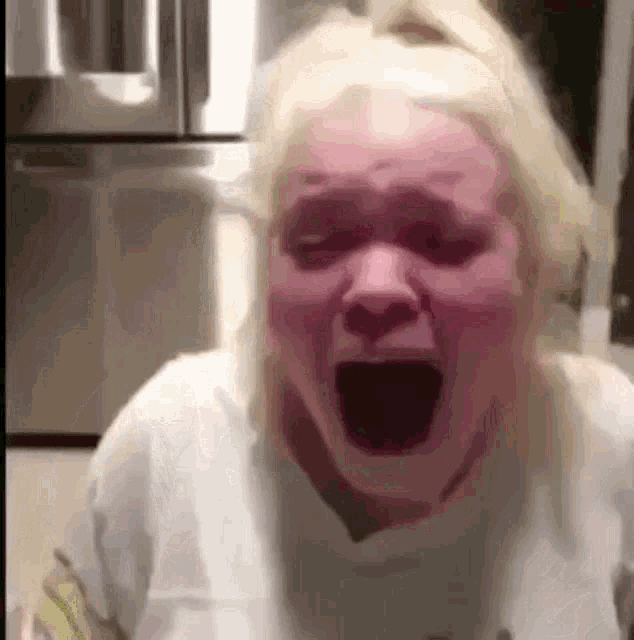 a woman with blonde hair is making a funny face with her mouth open .