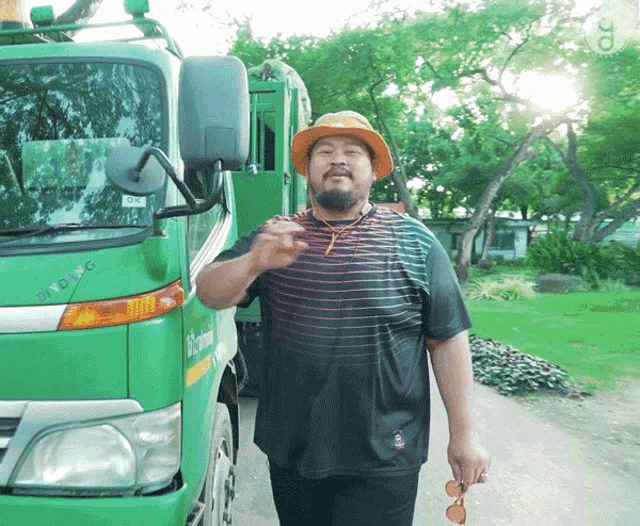 a man wearing an orange hat is standing in front of a green truck that says ' sydney ' on it