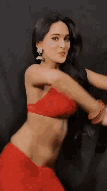 a woman in a red bra and red skirt is dancing on a black background