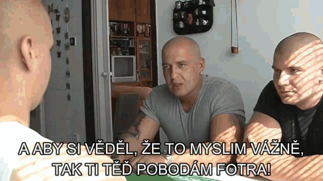 three bald men are sitting at a table and one of them says " a aby si vedel "