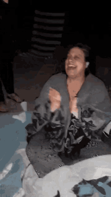 a woman is laughing while sitting on a blanket in the dark