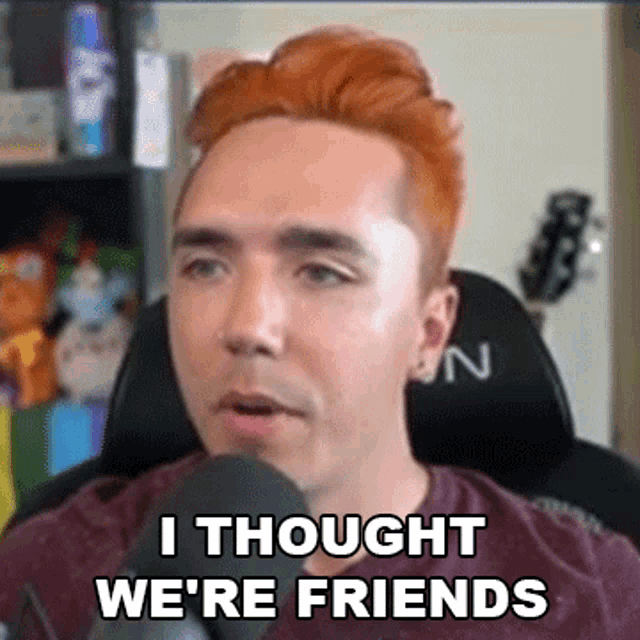 a man with red hair is sitting in a chair with a microphone and says `` i thought we 're friends '' .