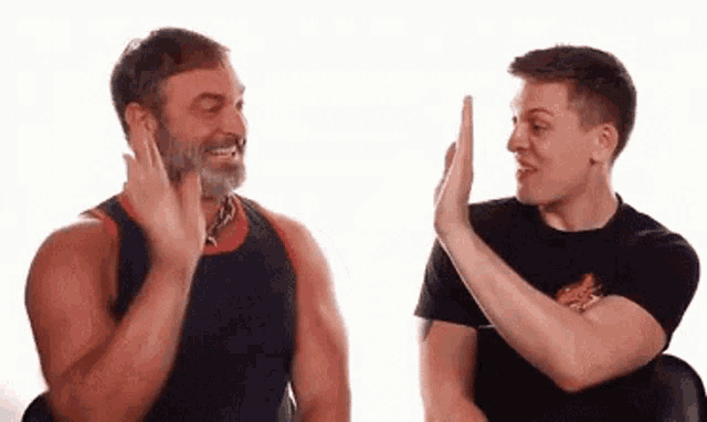 two men are giving each other a high five and smiling .