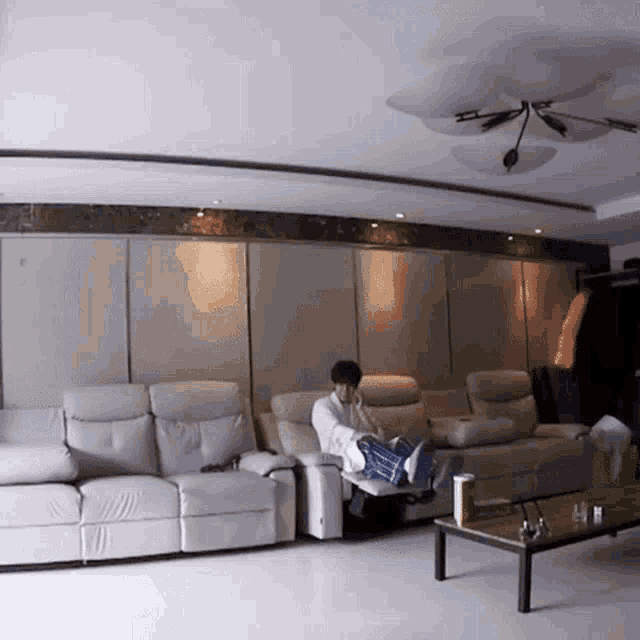 a man sits on a couch in a living room with his legs crossed