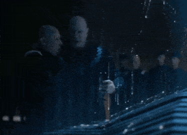 two bald men are standing next to each other in a dark room with water coming out of them