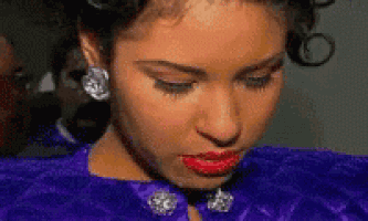 a close up of a woman 's face with red lipstick and a purple jacket .
