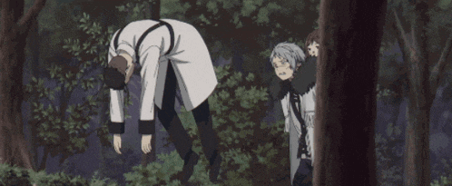a group of people are standing in the woods and one of them is laying on the ground