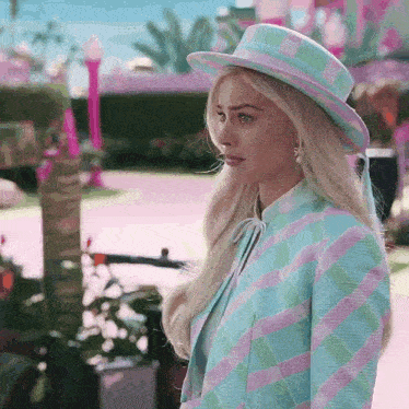a woman wearing a hat and a plaid jacket is standing in a park