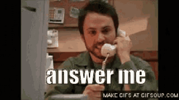 a man is talking on a telephone with the words `` answer me '' written on it .