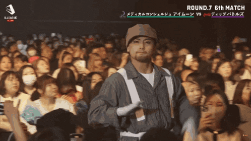 a man stands in front of a crowd with umi dip battles written below him