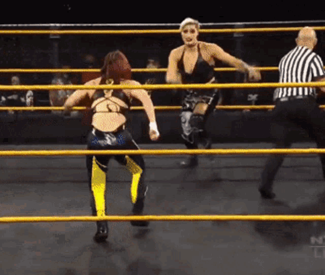 two women are wrestling in a ring with a referee