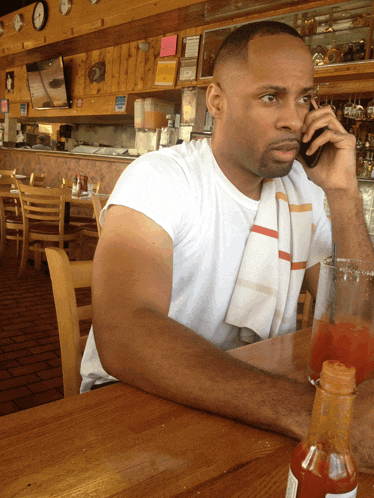 a man sits at a table in a restaurant talking on his phone