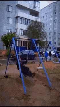 a person is swinging on a swing set in front of a building .