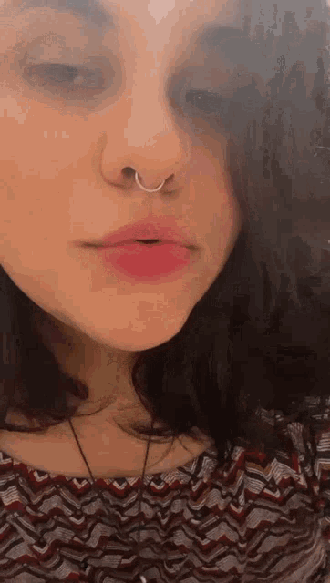 a close up of a woman 's face with a nose ring on it