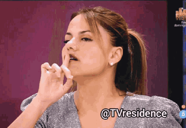 a woman is making a shhh sign with her finger to her mouth