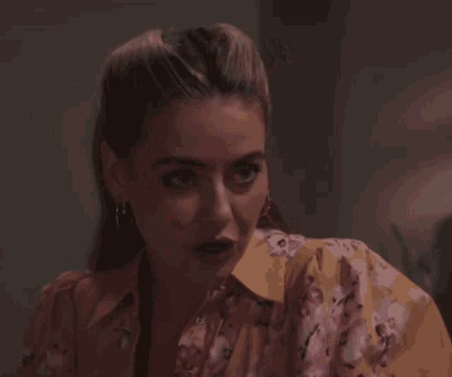 a woman wearing a yellow floral shirt looks down