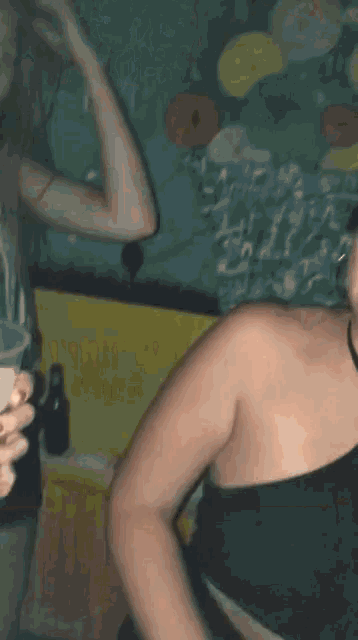 a woman in a black top holds a plastic cup