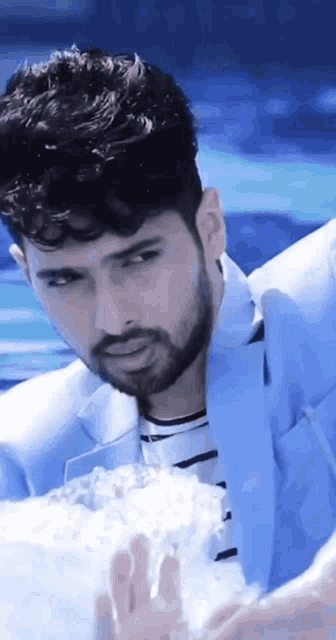 a man with a beard in a blue suit is holding a container of water