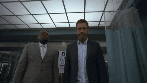 two men standing in front of a sign that says e