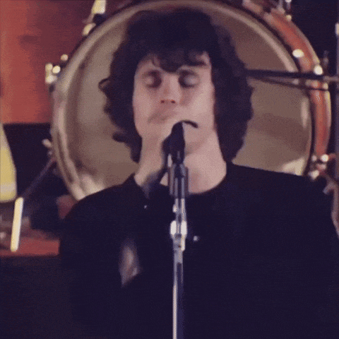 a man singing into a microphone in front of a drum set