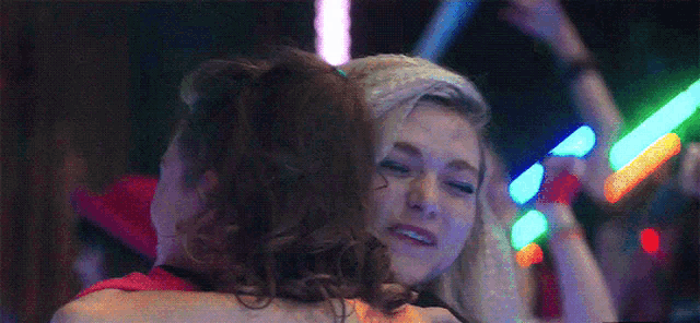 two women are hugging each other at a party with glow in the dark lights in the background