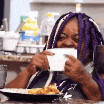 a woman with purple braids is eating a piece of food