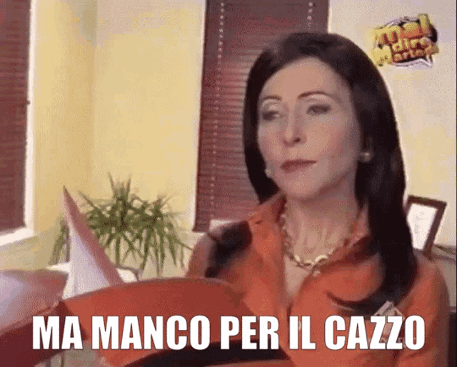 a woman sitting in front of a window with the words ma manco per il cazzo