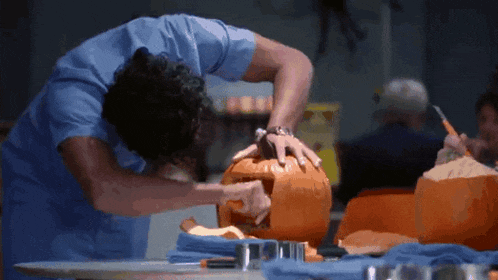 a man is carving a pumpkin on a table