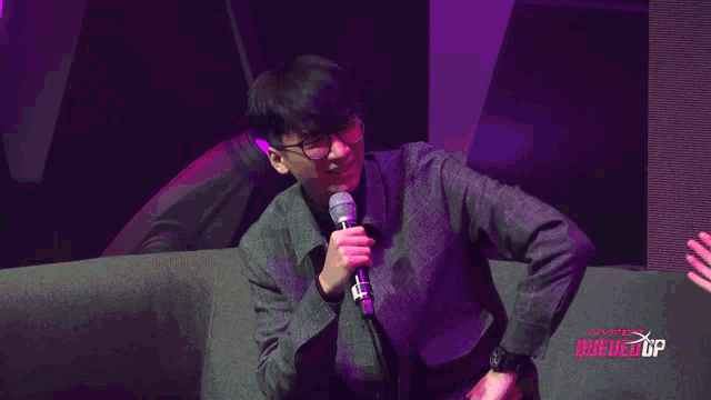a man sits on a couch in front of a sign that says hyper queues up