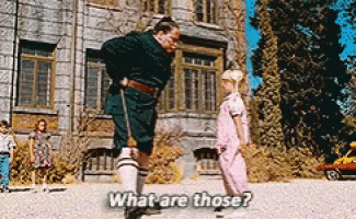 a man and a little girl are standing in front of a building and talking to each other .