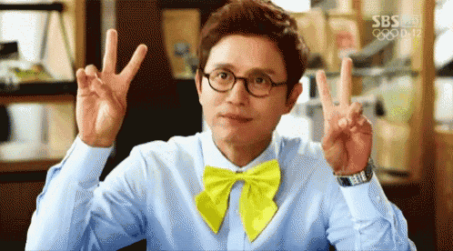 a man wearing glasses and a yellow bow tie is making a peace sign
