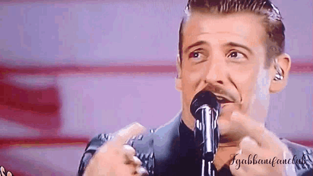 a man singing into a microphone with the name gabbanfanclub written on the bottom