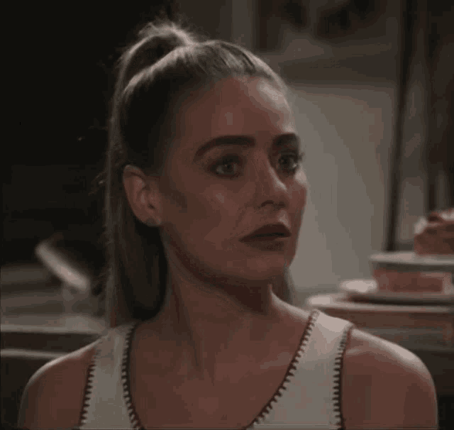 a woman with a ponytail and a white tank top