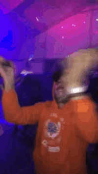 a man wearing a hoodie that says ' orange ' on it is dancing in a dark room