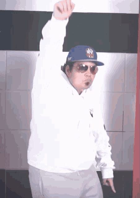 a man wearing a white hoodie and a blue ny hat is dancing