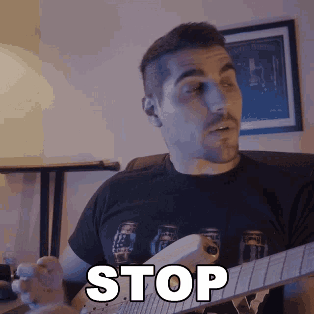 a man playing a guitar with the word stop written on his face