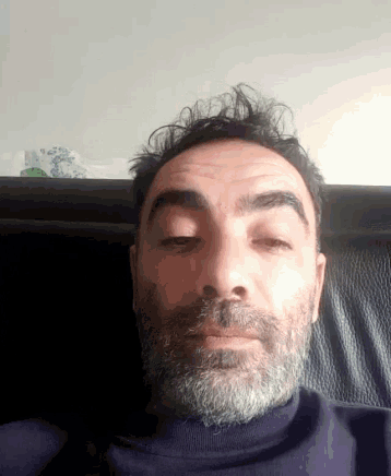 a man with a beard is sitting on a chair with his eyes closed