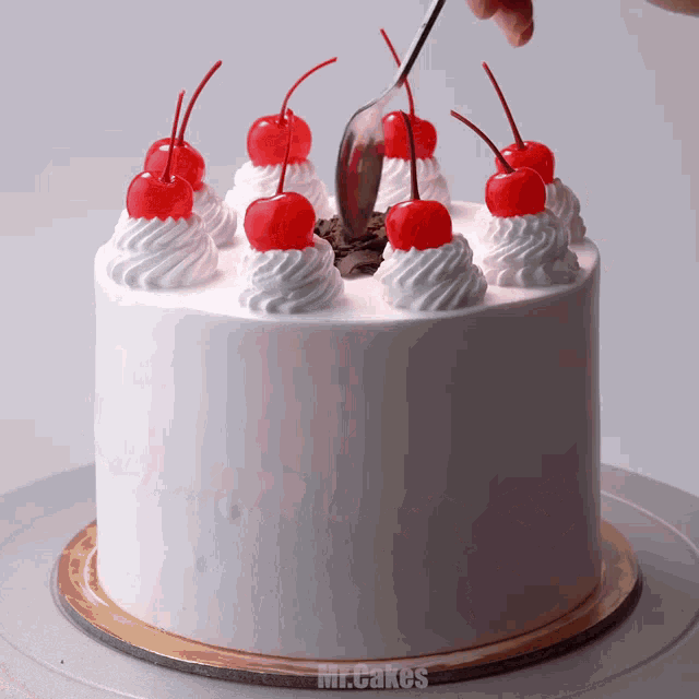 a cake with whipped cream and cherries on top is being decorated by mr. cakes