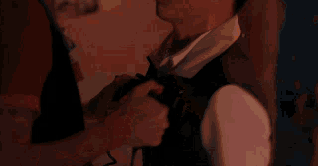a man with glasses holds another man 's neck in a dark room