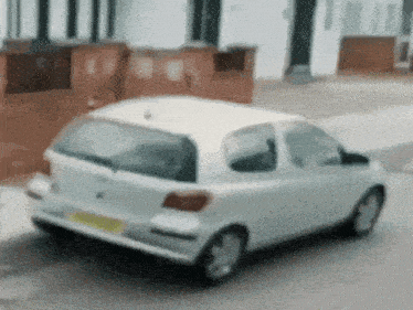 a white car with a yellow license plate is parked on a street