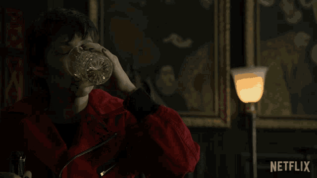 a man in a red jacket is drinking from a glass with the netflix logo in the background