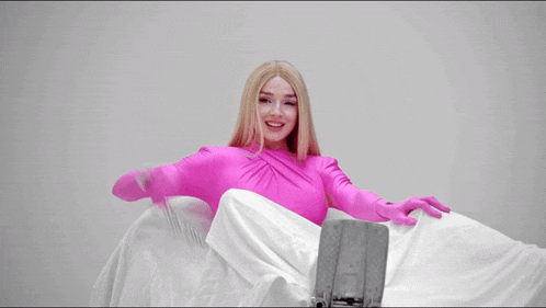 a woman in a pink bodysuit is holding a pair of scissors in her hand